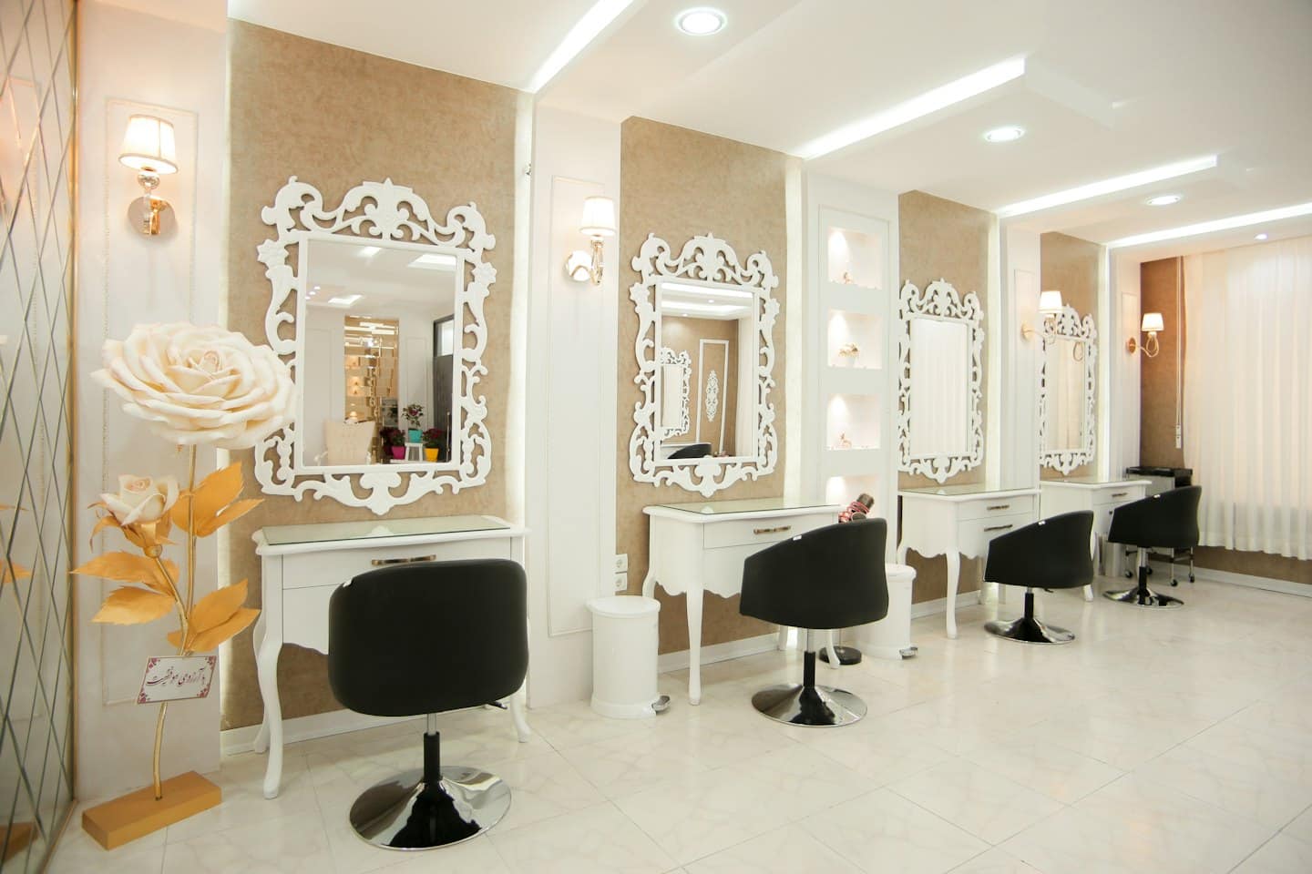 Interno di un moderno salone di bellezza con postazioni per parrucchieri e scultura decorativa di rose.